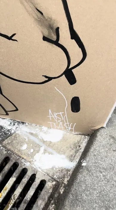 Drawn cardboard leaning above a drain grate on the street, Barcelona, Art Is Trash