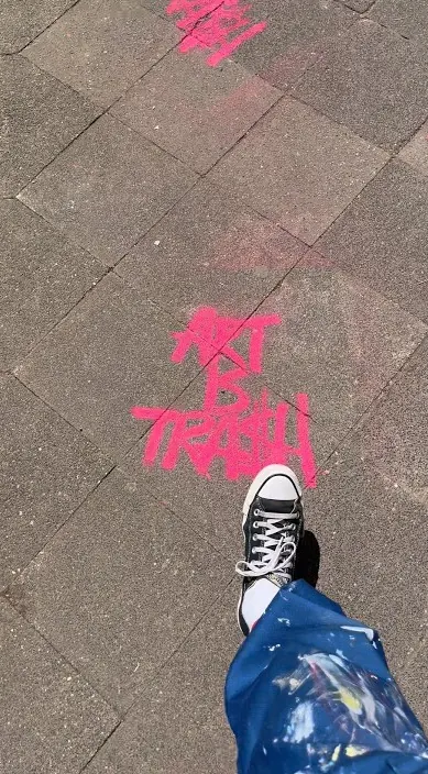 “Art Is Trash” sprayed in pink on the pavement during an exhibition, Düsseldorf